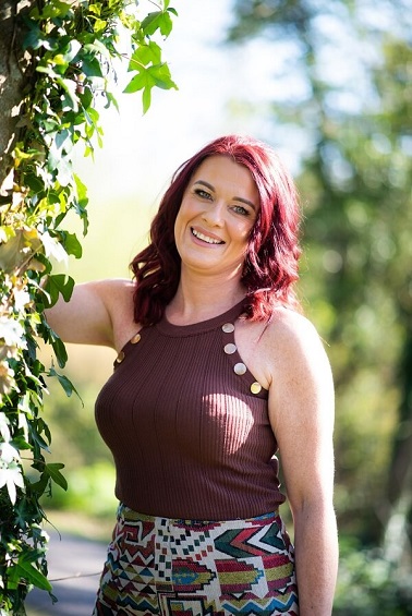 A photo of Lynda Emmett of Your Gift To You posing by a tree.